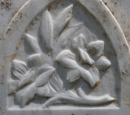 Close-up of 
grey marble headstone, flowers