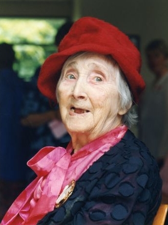 A charming coloured 
   head and shoulders shot of Ann in an elegant navy, lily-leaf textured jacket, and a deep pink, probably silk blouse, 
   wearing a red slouch-hat. copy of the written advertisement, with lists of food.