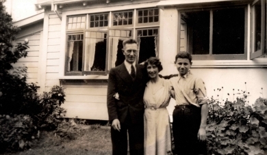 Ann between William and Jozef in the garden. William in a suit and tie, ann hatless and Josef in khaki shirt and 
   trousers