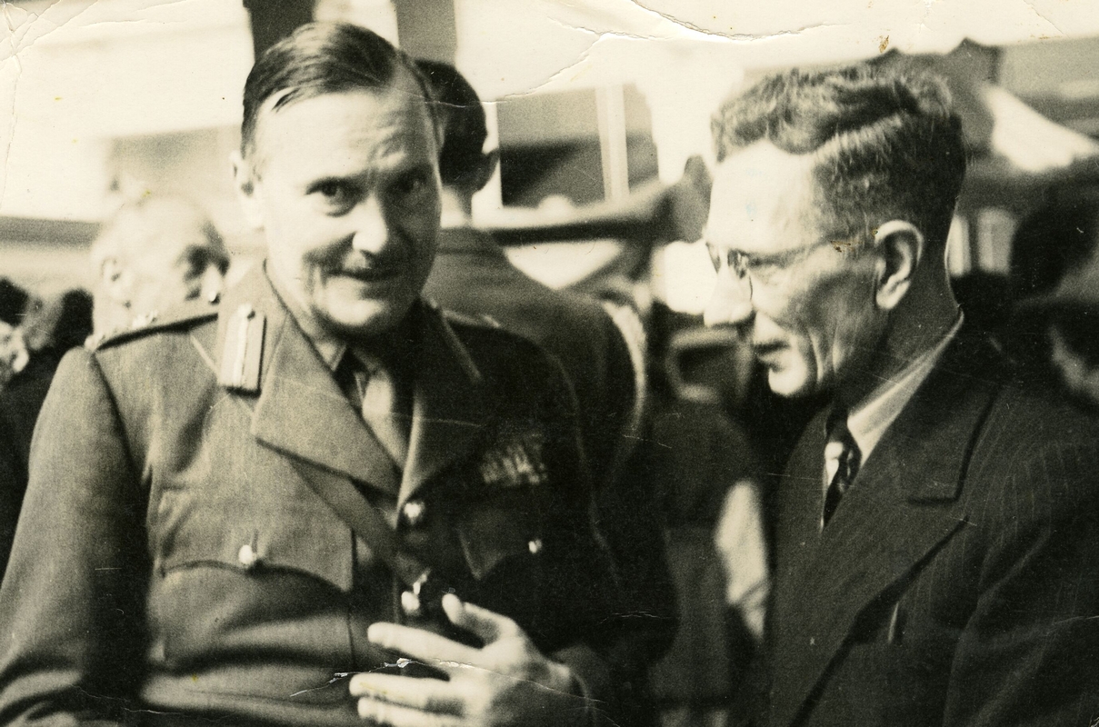 Head and 
   shoulders shot of William Jacques looking down and talking to Gen Freyberg, who has just looked up to the photographer.