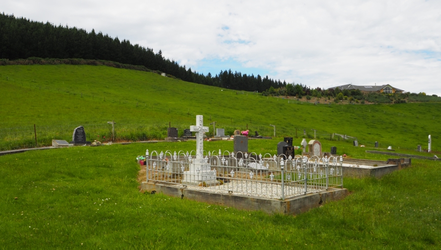 View of the 
Waihola cemetery with Paul and Eva Baumgardt's gravesite, enclosed with a fence, in the foreground.