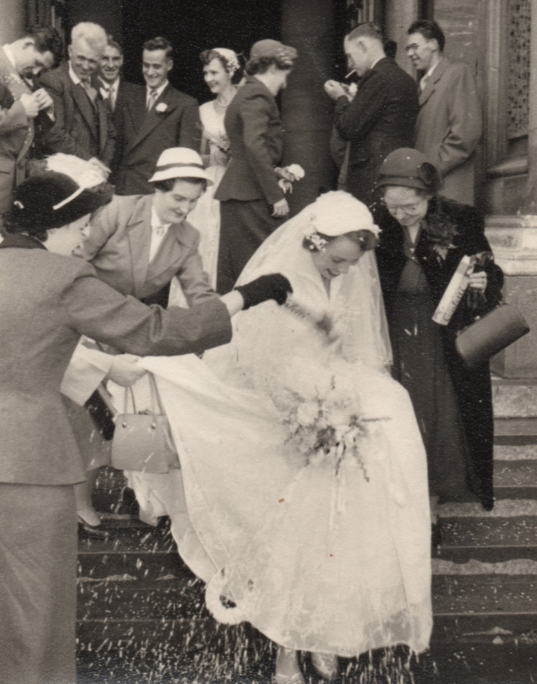 Henia looking 
down as she negotiates the steps of the cathedral and wedding guests throwing confetti