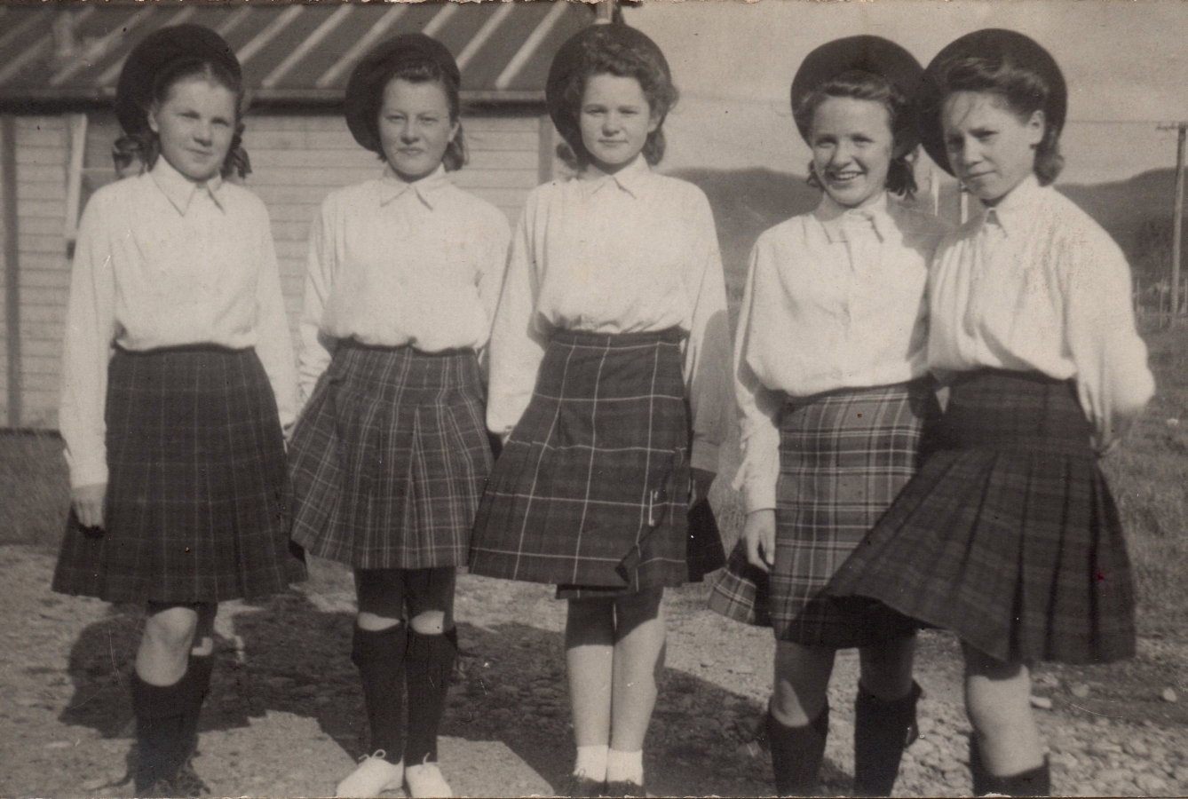 The five girls  
pose outside wearing their kilts, white shirts and Scottish berets