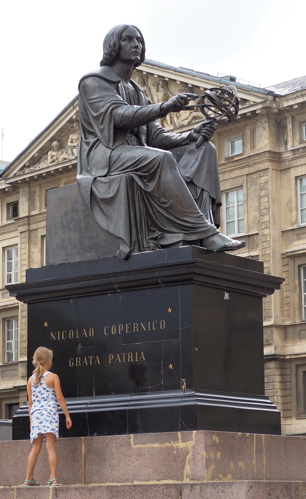 A little girl stands on the 
steps of the plinth, seemingly reading the writing, Nicolao Copernico, Grata Patria. She is dwarfed by the monument, four 
times her height