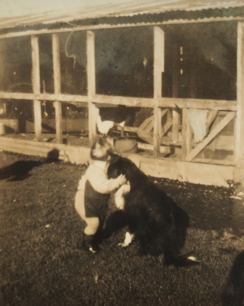 A sepia 
   photograph of a toddler with its head cuddled next to the dog's.