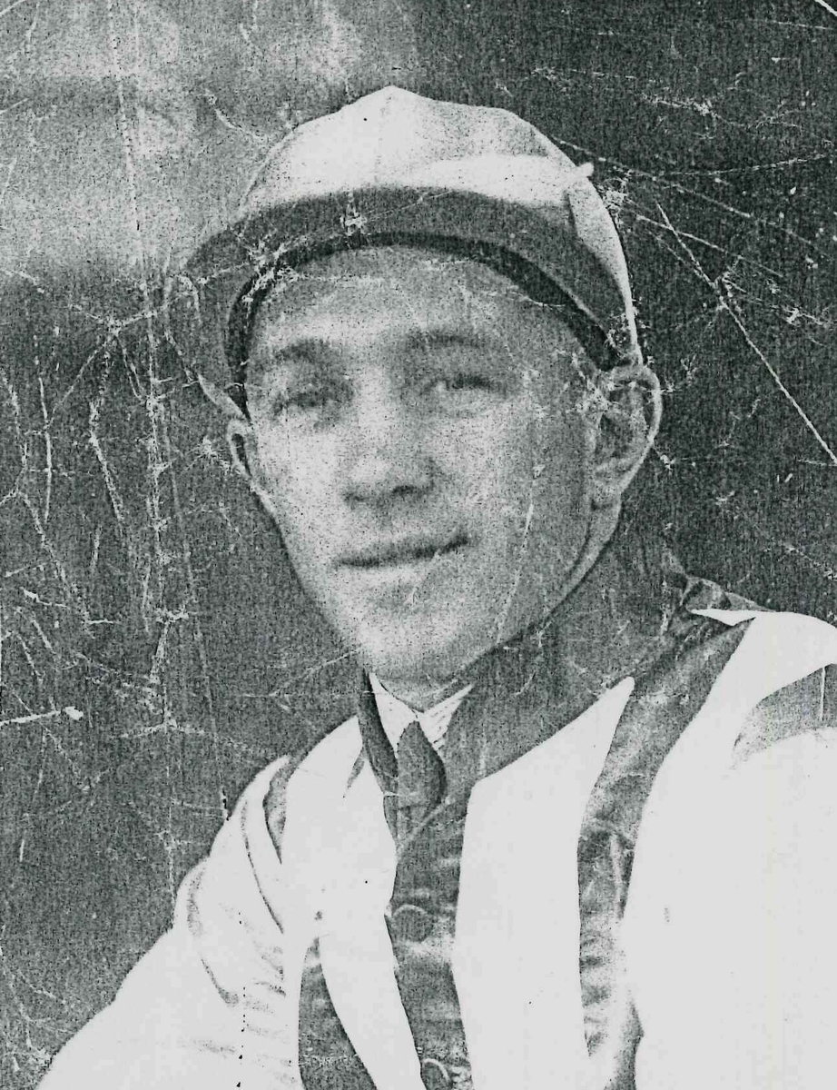 A black and white 
   head and shoulders shot of Keith Voitre in riding uniform. Crinkly with age, but he is smiling.