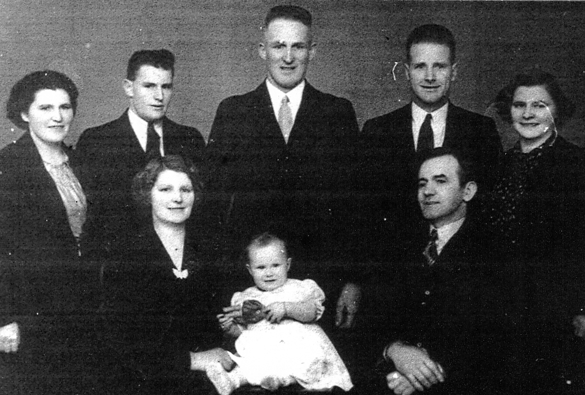Black and white 
   studio portrait of the Yearbury family, with Faye in white in the middle.