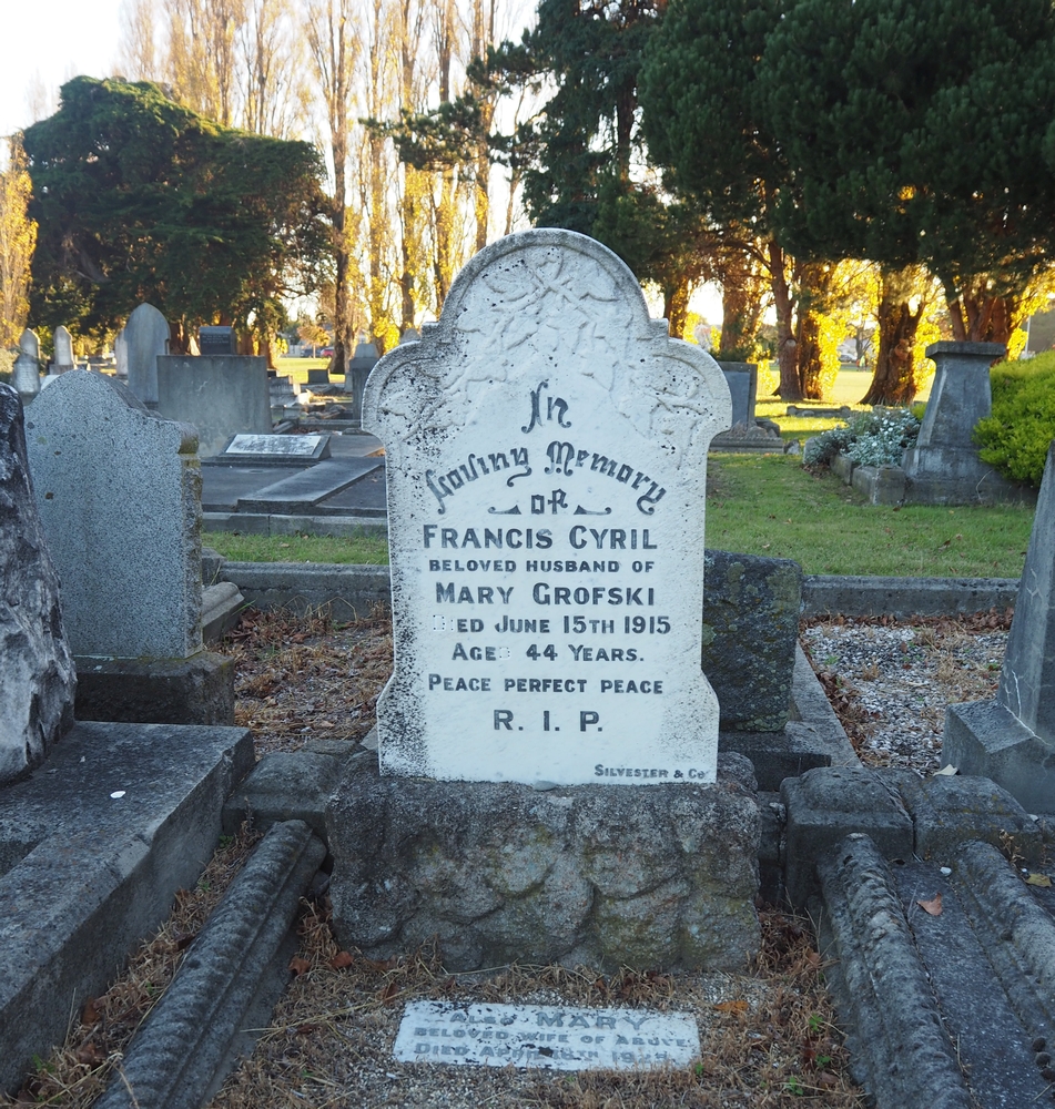 Francis Cyril 
Grofski's headstone in lowering sunlight.