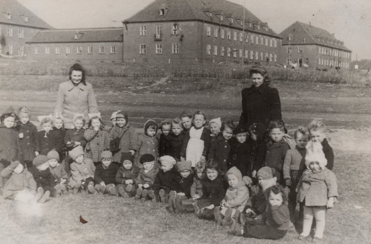 A group of young 
children in the foreground, a few hundred metres from the Flensburg DP buildings