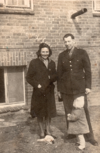 The  
family outside an old brick building, one of the three windows at ground level. Paweł  and Irena are looking at the camera, 
and Halina looking up at them.