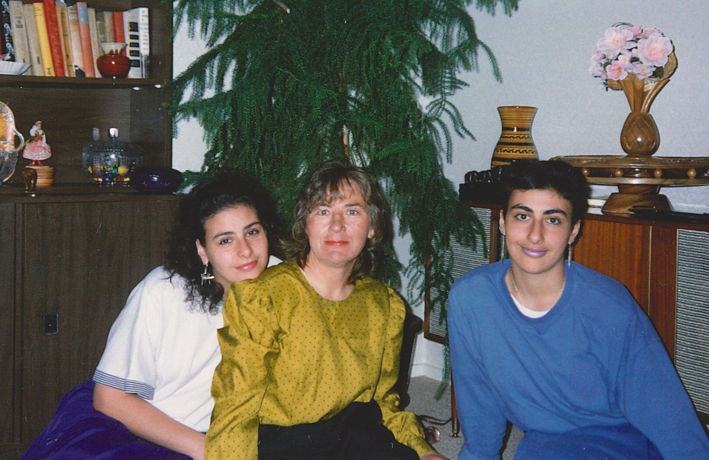 A coloured 
photograph with Halina and her daughters sitting on the floor in front of a Christmas tree. Halina is in the middle. One 
daughter has her chin on Halina's shoulder