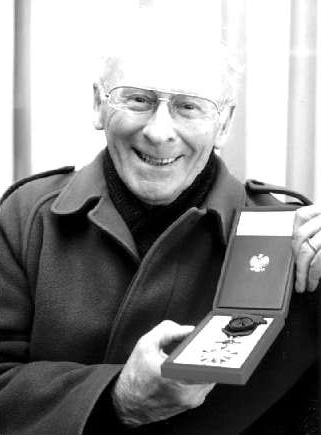 black and white 
head shot of a smiling Mr Henderson with his Polish medal