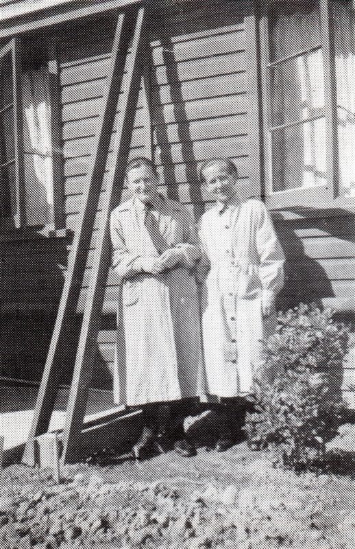 black and 
   white pic of two nuns in front of a wood-board building