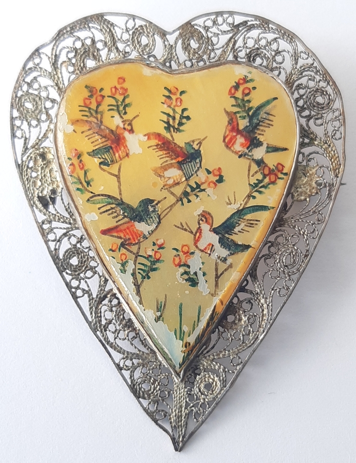 A heart-shaped brooch, 
filigree metalwork on the outside and five painted birds with flowers on the inside, slightly tarnished now but still 
beautiful.