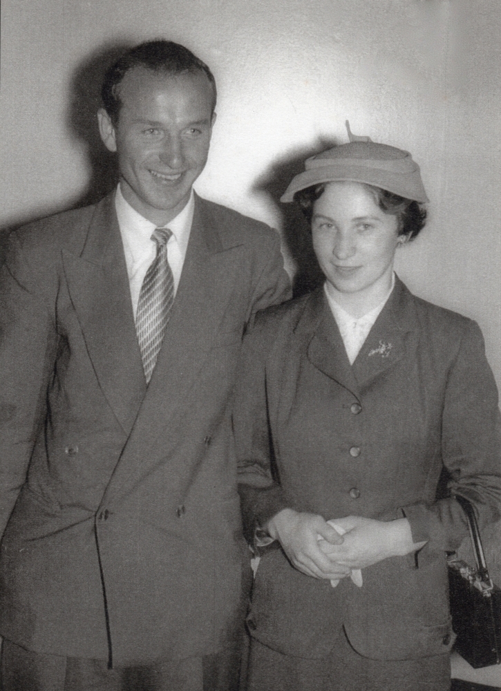 A black and white 
photograph of the two in mid-toned suits, Jan smiling to someone on the right of the phnotographer. Irena, wears a hat, holds 
gloves and with a handbag on her arm, is looking demurely at the potographer.