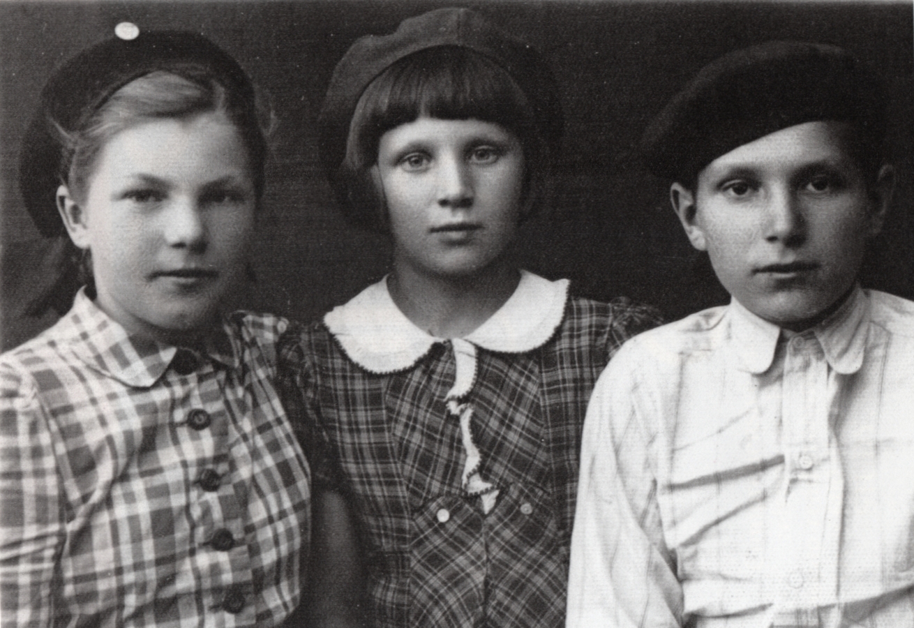 A black and white 
photograph of the three neatly dressed siblings. Czesław is in a light shirt buttoned to the neck, and the girls are wearing 
checked dresses; Zofia's buttoned to the collar and Irena's with a prettier, white collar. All have serious expressions.