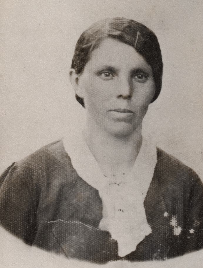 A black and white 
head and shoulders shot of Leokadia, with her hair brushed back, a hairgrip keeping it away from her eyes, serious, and 
wearing a dark dress and wite collar