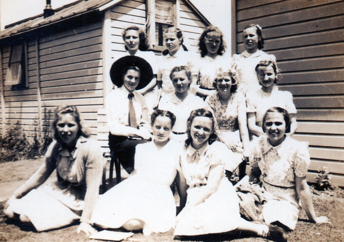A group of 12 of the older 
girls, four at the back, four seated and four sitting lady-like in front. Most are smiling. Zofia is seated on the left, the 
only one wearing a shirt and tie and dark skirt. All the others are wearing light dresses.