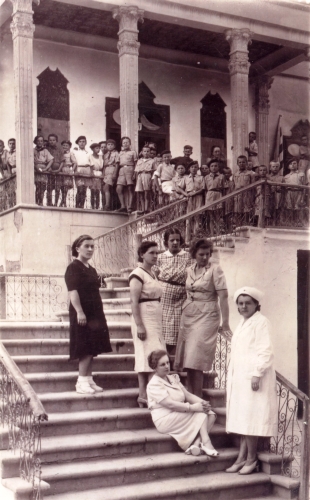 Group of boys and 
their caregivers on steps outside Isfahan mansion