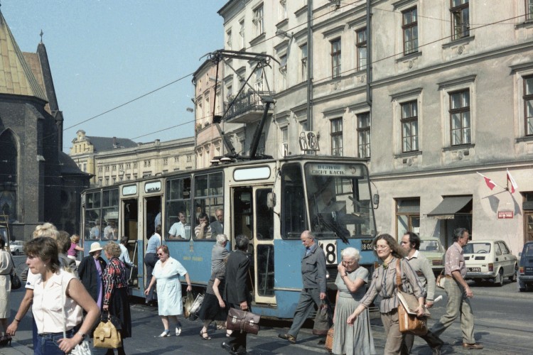 Kraków city 
centre, people walking across the road with tram in middle