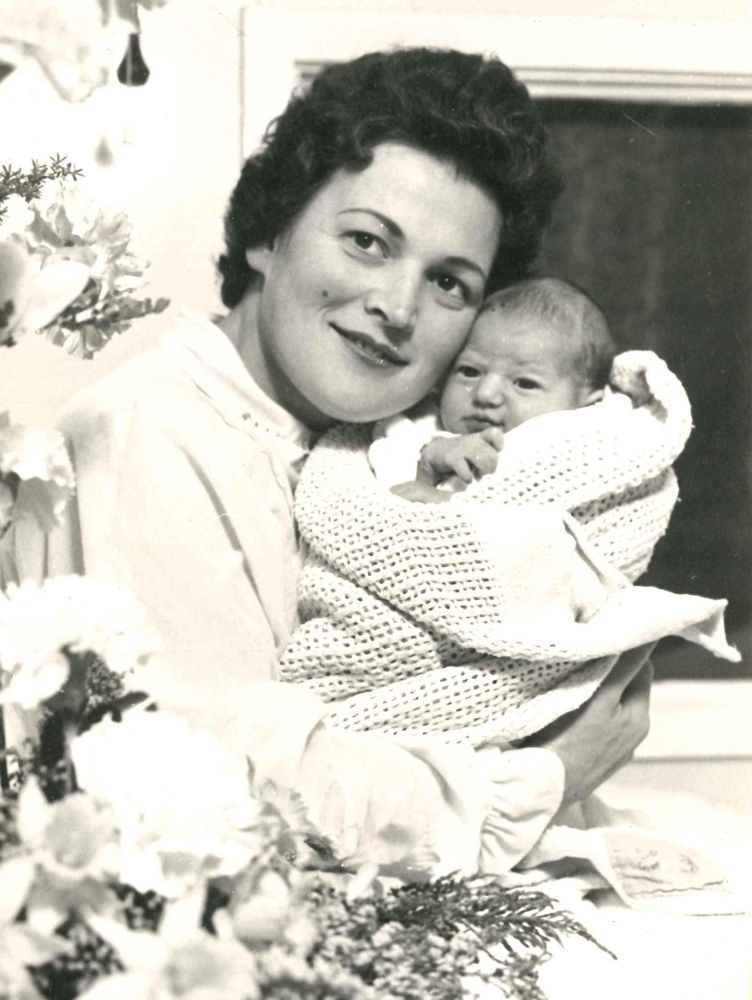 Black and white 
hospital-bed photograph of Marysia Jaskiewicz, dressed in a light night-jacket, smiling and looking up to the left, and 
holding her new-born daughter, wrapped in a light blanket, and with the usual new-born squished look.