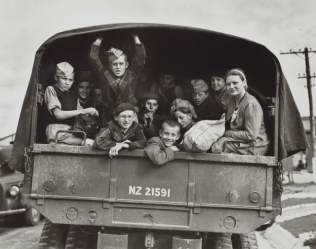 Polish boys with woman 
caregiver looking from the back of an army truck