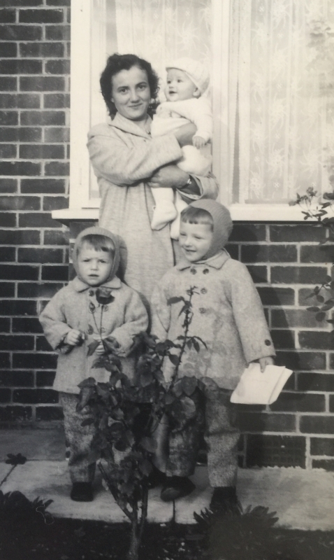 Joanna, 
holding a baby with her sons in front of her, all dressed in coats.