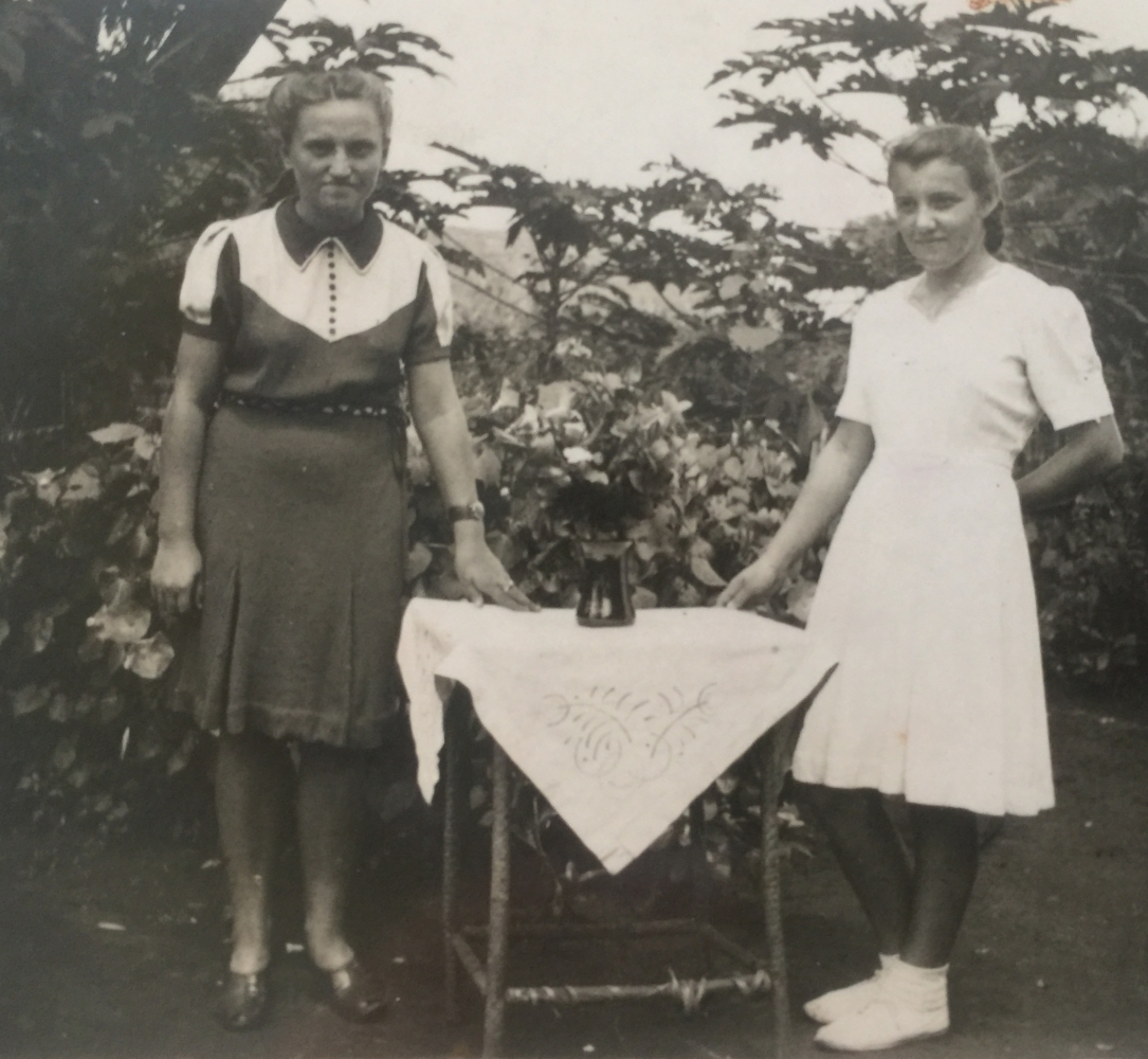 Joanna dressed in white and a friend standing on either side of a table with a white tablecloth