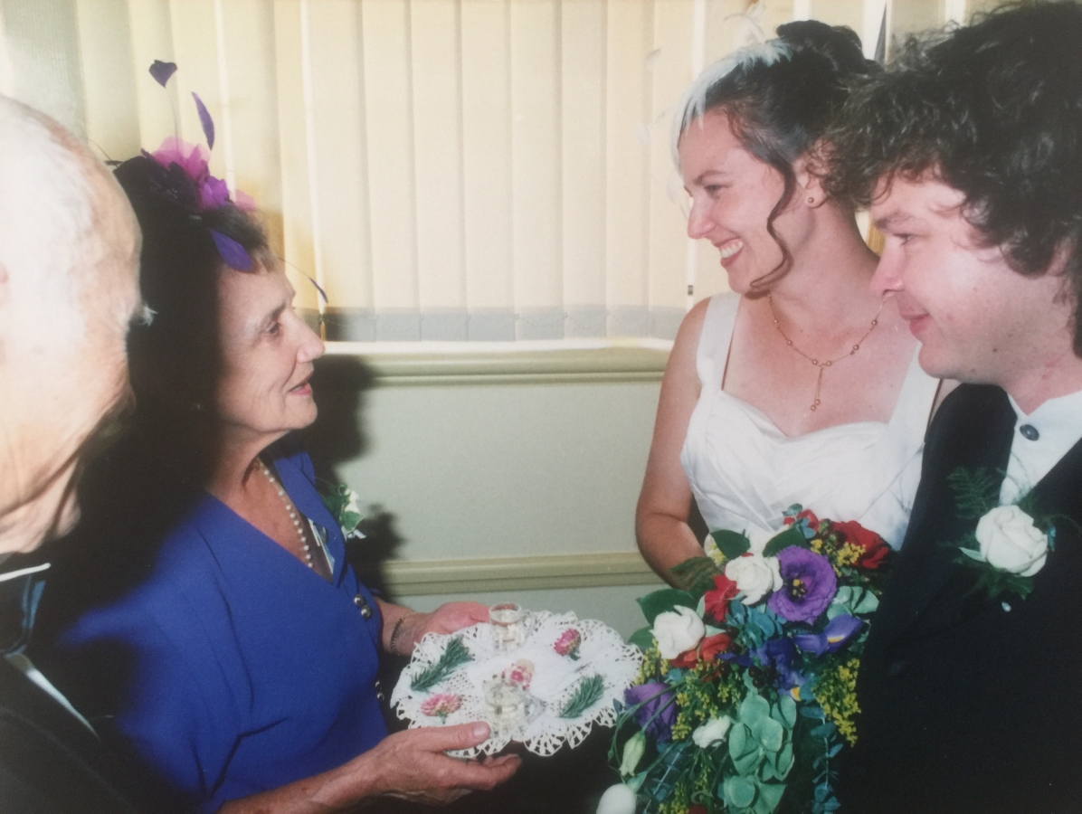 Joanna greets 
her daughter and new son-in-law with a dainty tray covered with a crochet cloth and decorated with greenery and rosebuds. The 
two shot glasses are visible. Tadeusz is at Joanna's side, back to the camera.