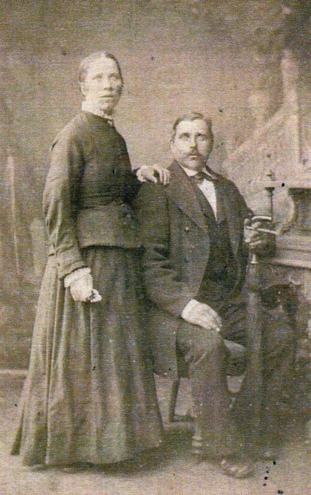 A blurry 
studio photo of Franz, seated, his hand leaning on a closed umbrella and Pauline, standing with her hand on his shoulder.