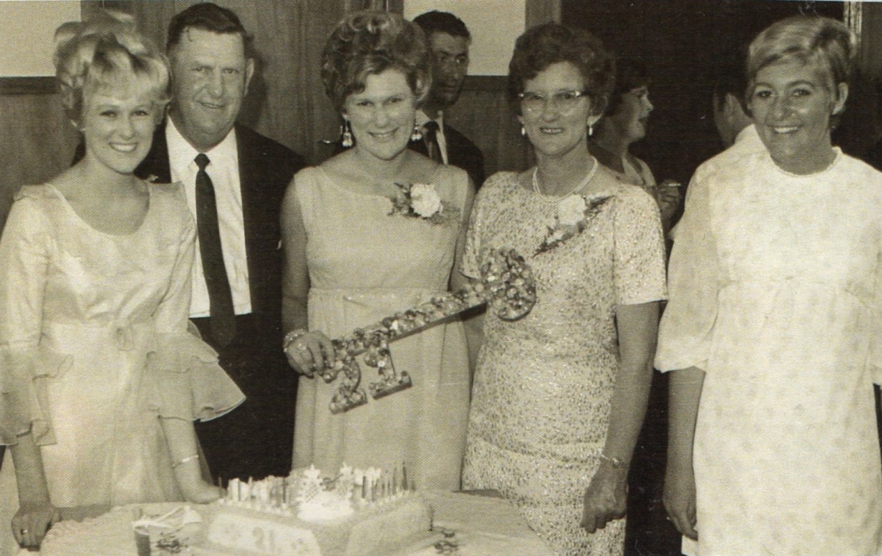 A blurry 
photo of Len and Katherine with Patricia in the middle holding a huge 21st key and her sisters on the outer sides.