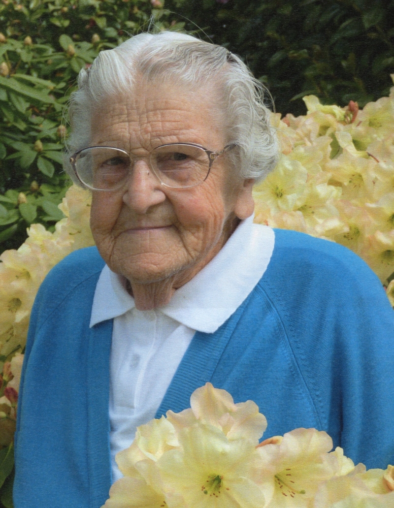 Therese Kowalewski 
flanked by her cousinsdressed in a blue cardigan and surrounded by yellow-cream flowers, probably gladioli