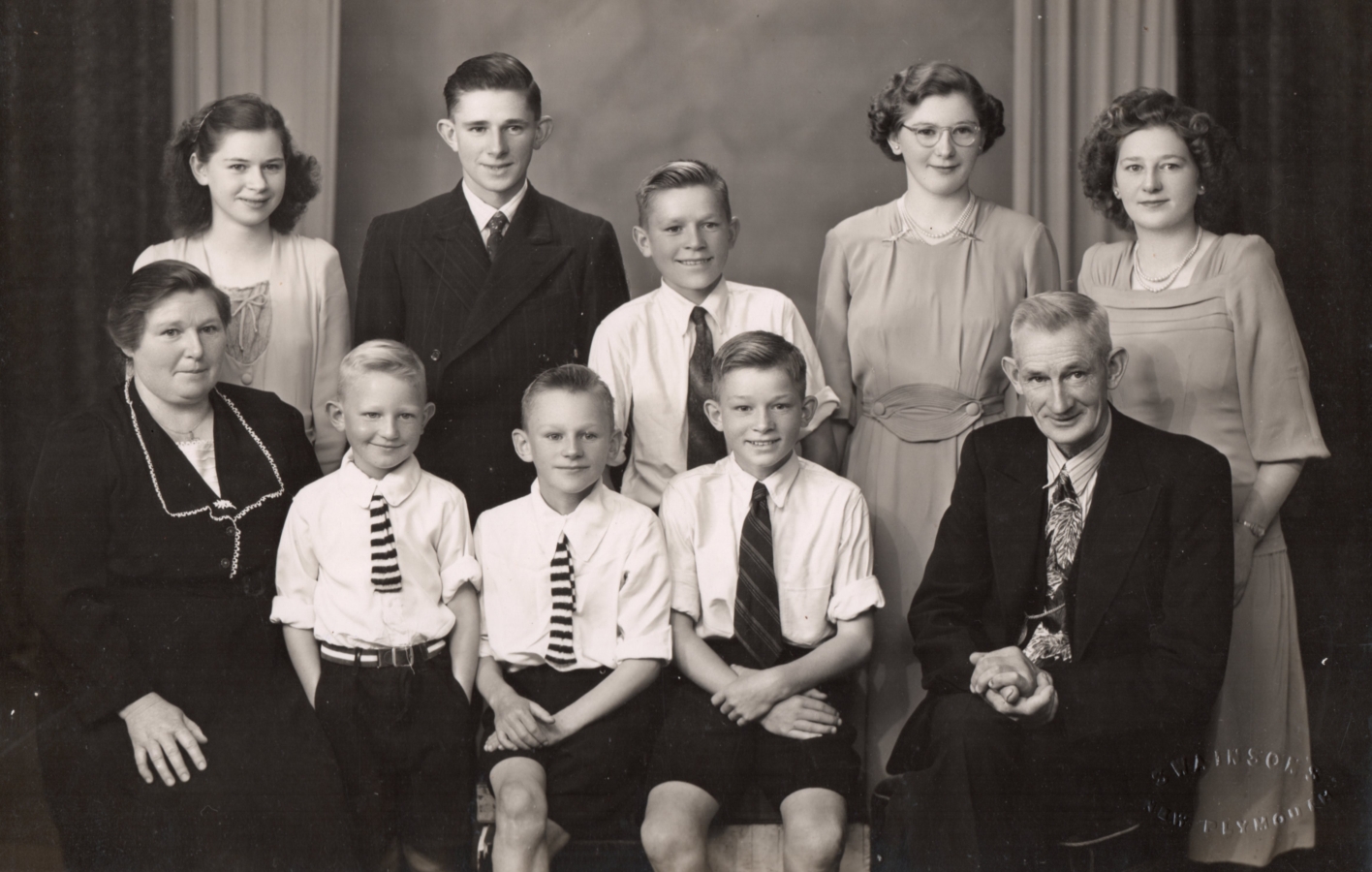 Black and white
studio photograph of the family: Jacob and Joseph in suits and ties, and the four younger boys in white shirts and ties, 
Ellen in a formal dress suit, and the girls in dresses. All are smiling sweetly.