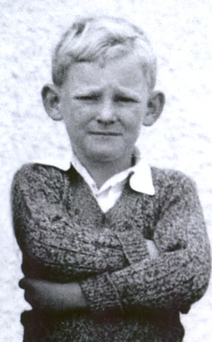 Allan 
Hughes, arms crossed, staring into the camera, as a Standard One pupil in 1941