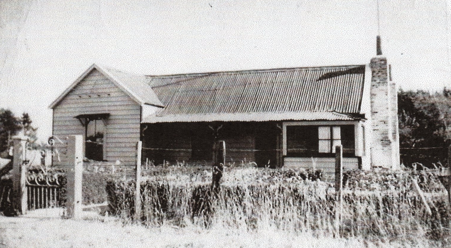 A 
black and white photograph of the simple bungalow with corrugated iron roof.