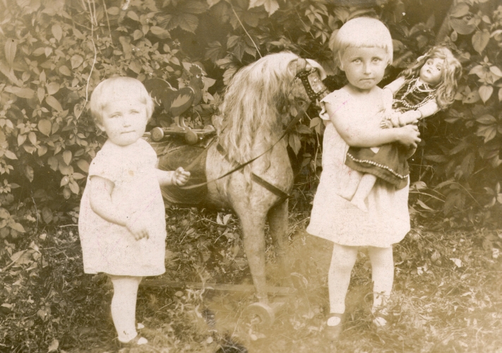 Janina and 
Romka Marchewa, aged about two and four, with doll and wheeled horse in garden