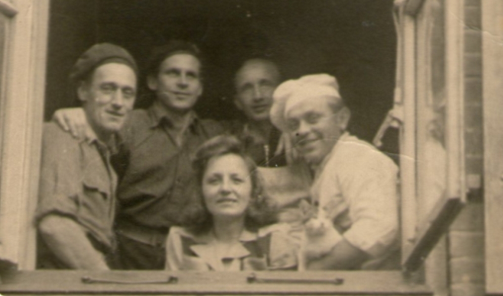 Antos Sarniak, holding a cat, and friends looking out of a window in post-war Germany.