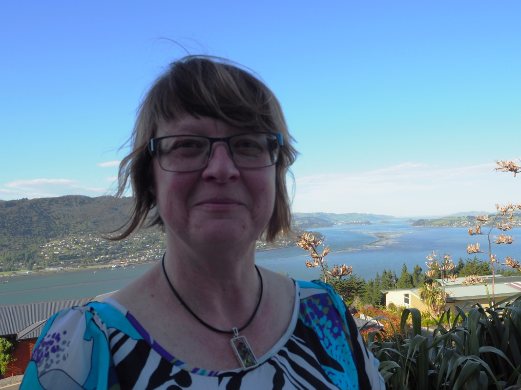 Bożena 
Misiewicz-Haug on a balcony at her home, with the Otago peninsula in the background