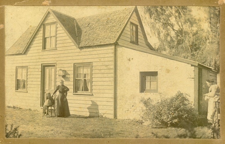 Wood and 
sod house with two unknown woman and an unknown child
