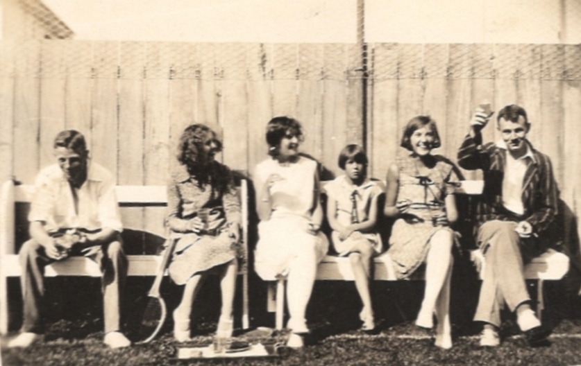 John Lovelock with Madeline, Rayena, a neighbour, Mavis and Don Sinclair junior sitting on a bench next to the tennis 
court