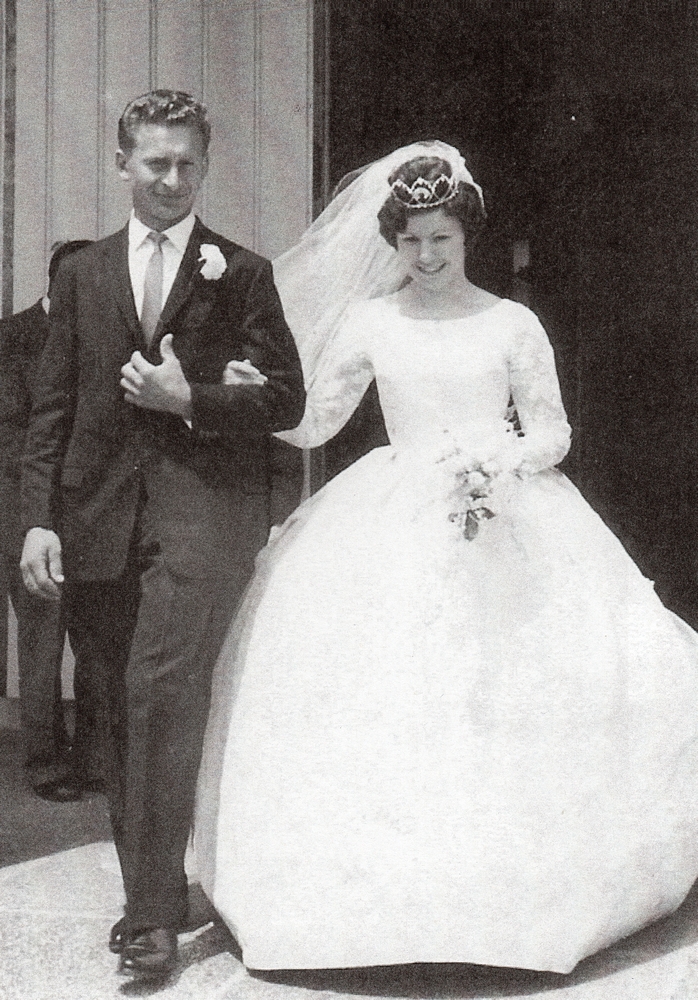 Black 
and white pic of Zenona and Michał walking out of the church. Wind is pushing Zenona's short veil. Her dress is long-sleeved 
and with a full skirt Wide smiles.