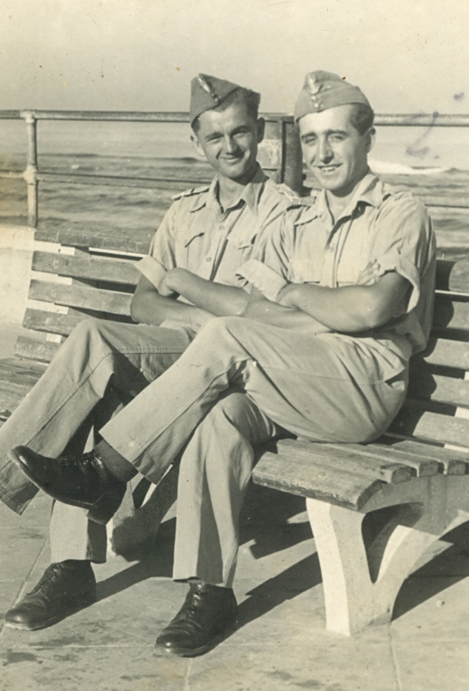 Władysław and a friend sit on a bench at the seaside