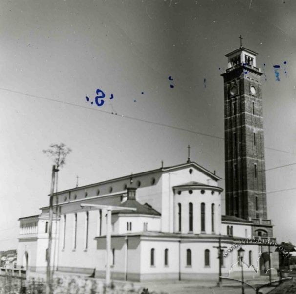 Black and 
white picture of the church, white, with the high tower next to it in a darker brick