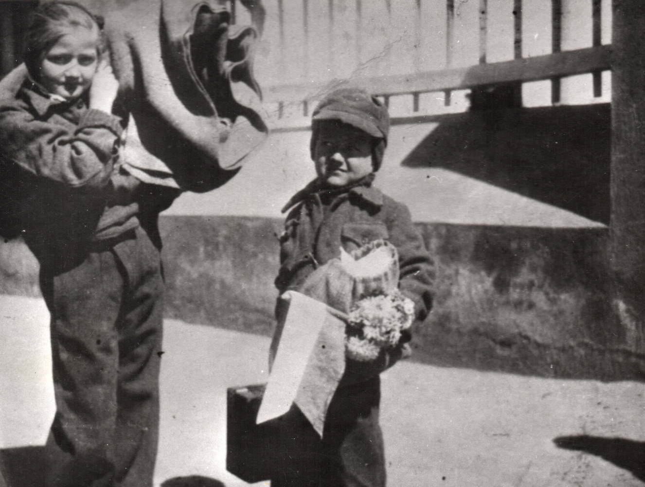 Zofia holding a bedroll 
over her shoulder and Witold with a small suitcase, a bundle, a Polish flag and some flowers in his hand.