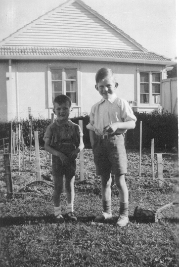 Two young 
   boys standing in the garden of a house