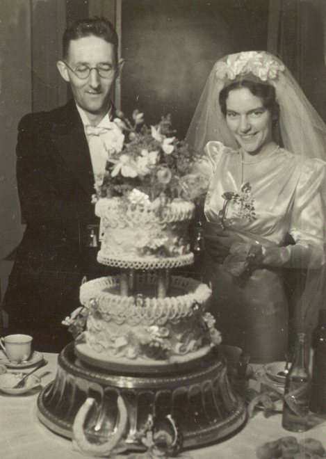 black and white photograph of the newlyweds behind a huge wedding cake