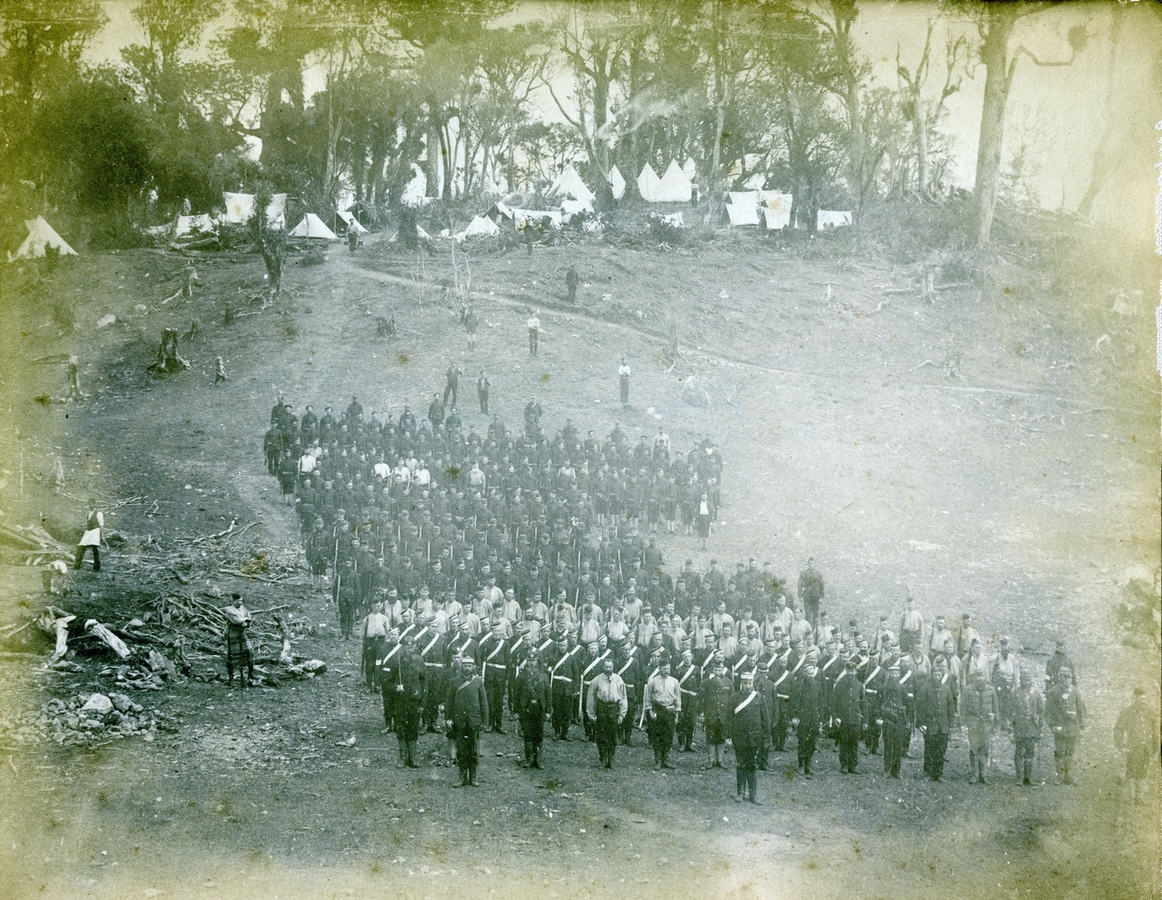 The 
AC getting into formation, facing forward. An active pic of the soldiers om the side of a hill, tents in the background, and 
various hangers-on.