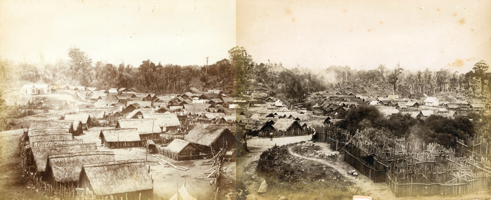 The joining isn't 
perfect, but the two photographs were taken at the same time. A homestead on the left, on a raised mound, and about 80 
thatched huts, trees in the background and a fenced area in the right foreground, possbily for animals and gardens.