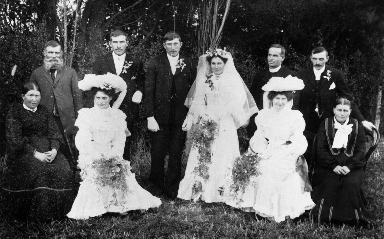 Black & 
white photograph of the main wedding party taken in a garden.