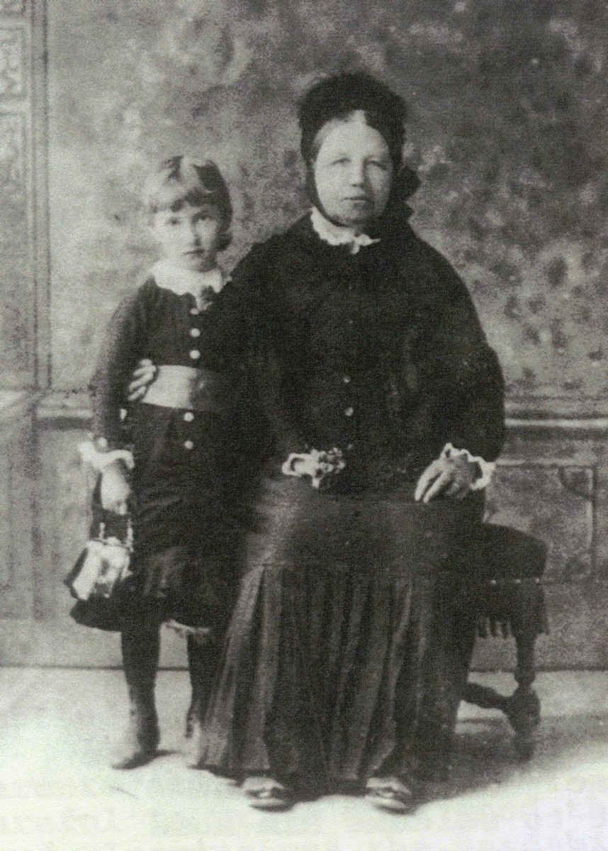 A formal 
studio portrait. Rosalia's fingers can se seen on her granddaughter's waistband. The child has one hand on Rosalia's lap and 
the other is holding a handbag